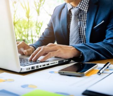 homem-de-negocios-que-trabalha-no-escritorio-com-documentos-de-dados-de-laptop-tablet-e-graficos-em-sua-mesa.